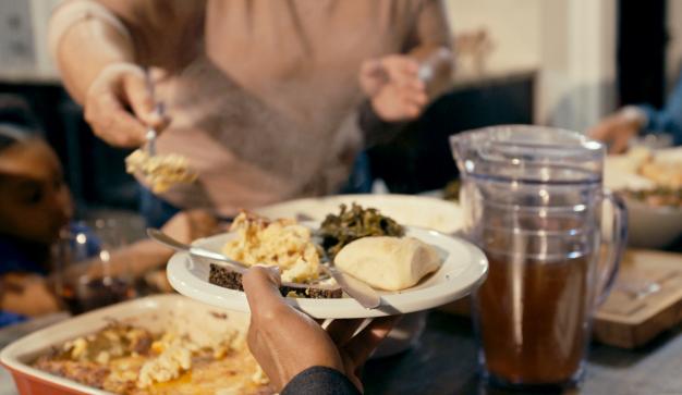Hands passing a plate of food at a Sunday Dinner