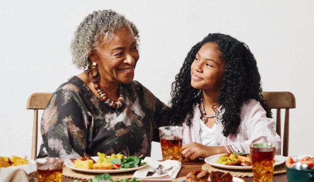 Grandmother and young girl gathered around a family meal