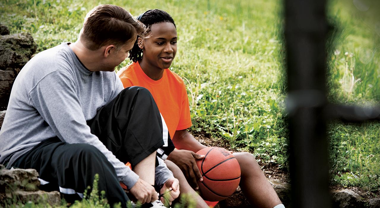 man mentors youth male holding a basketball