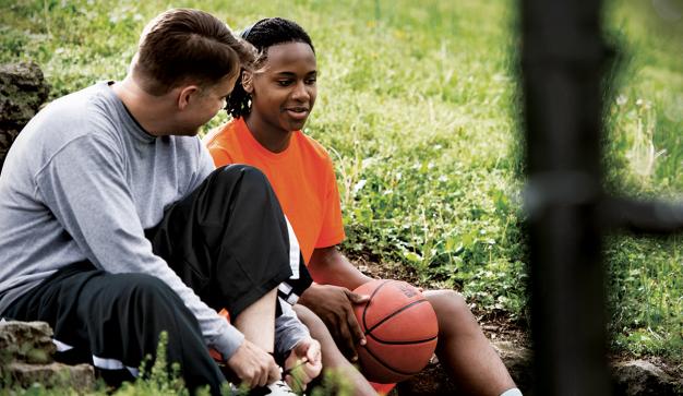 man mentors youth male holding a basketball