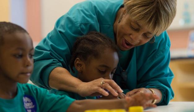 lady helping young kids with education project