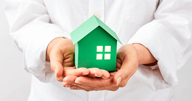 hands holding a green paper house