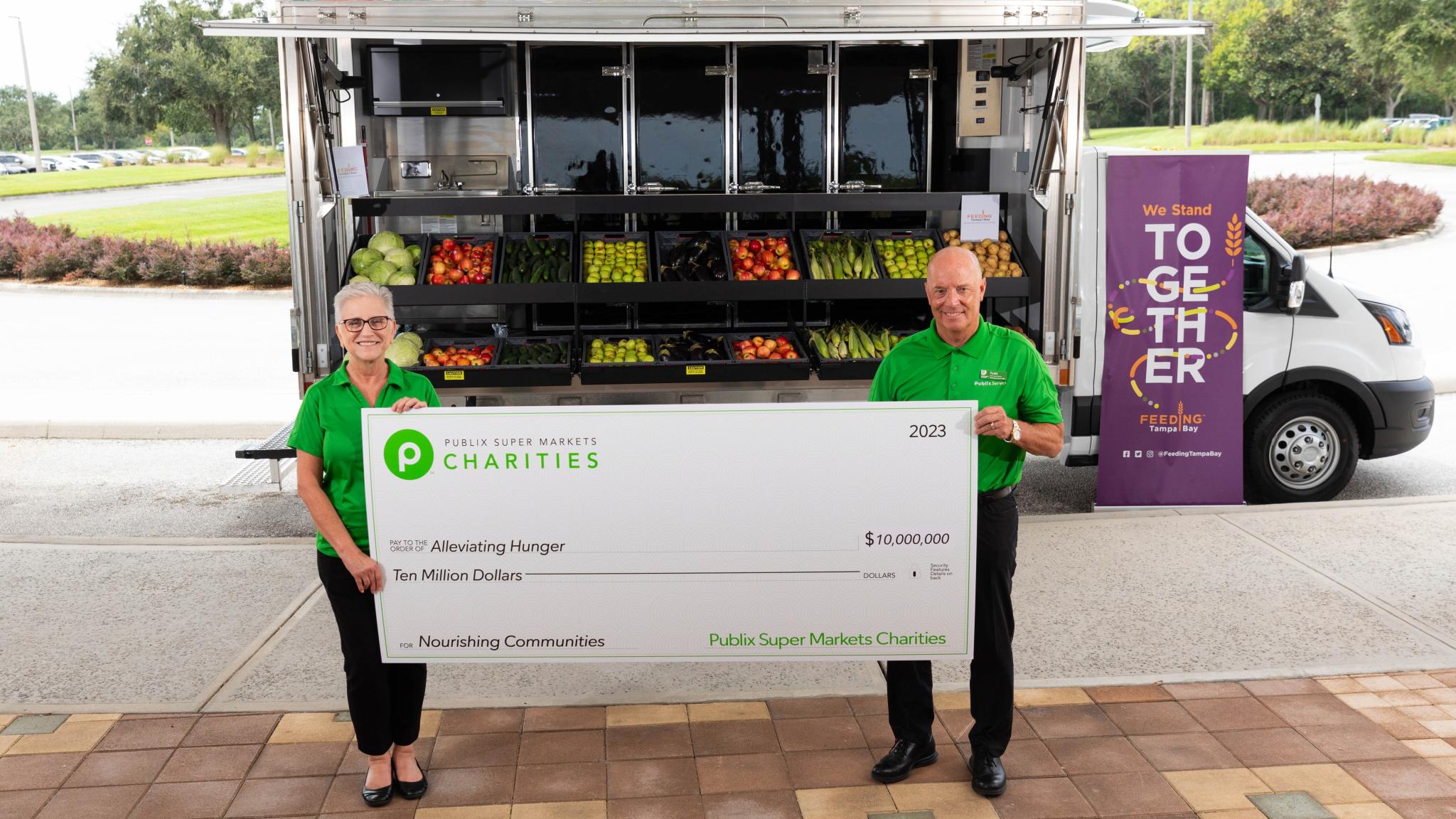 two people holding a giant charities check