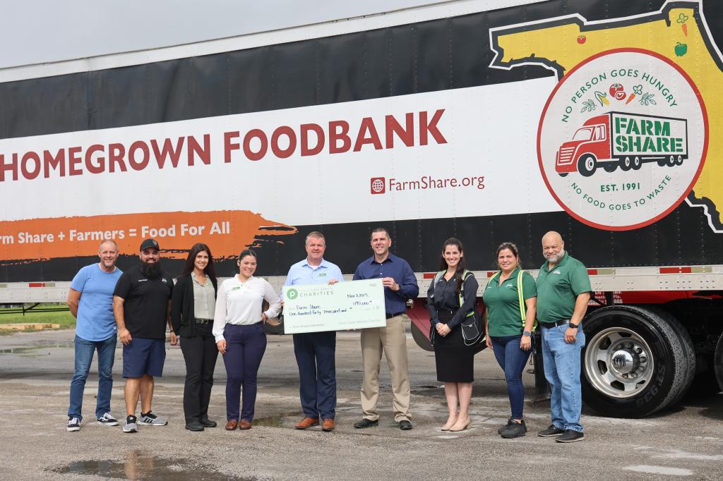 Group holding a check in front of Farm Share truck