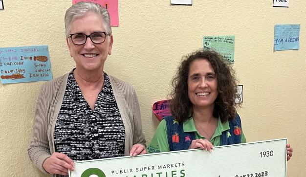 a woman and a young girl holding a large charity check