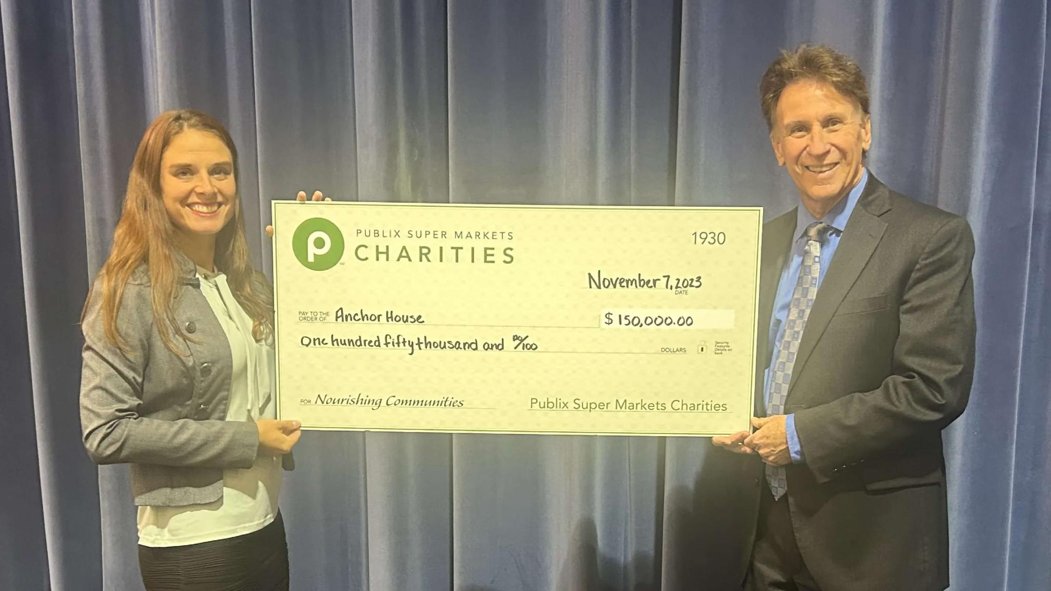 Two professionals holding a large charity check