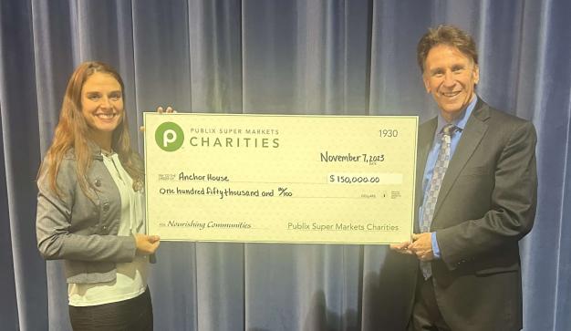 Two professionals holding a large charity check