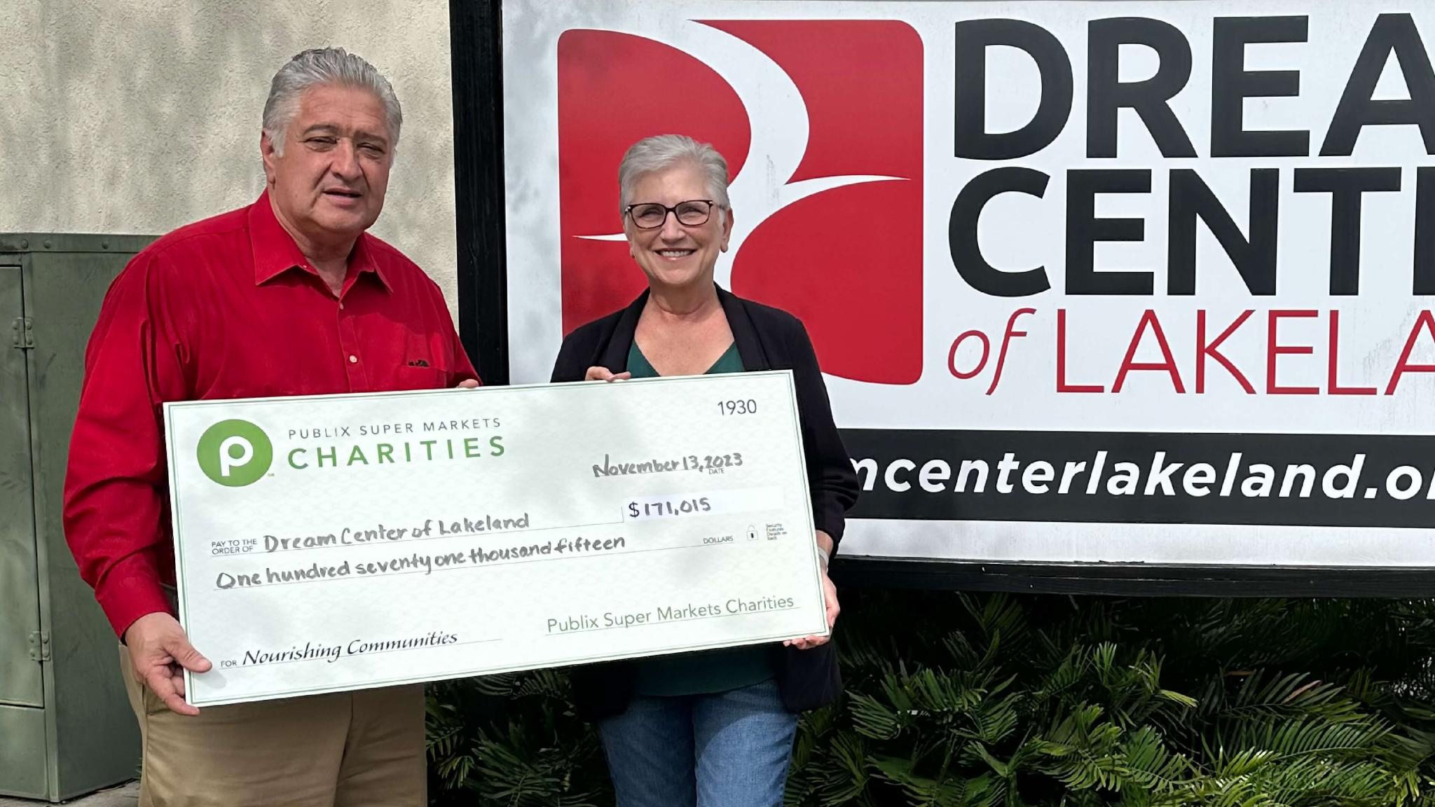 people holding a large charity check outside of Dream Center of Lakeland