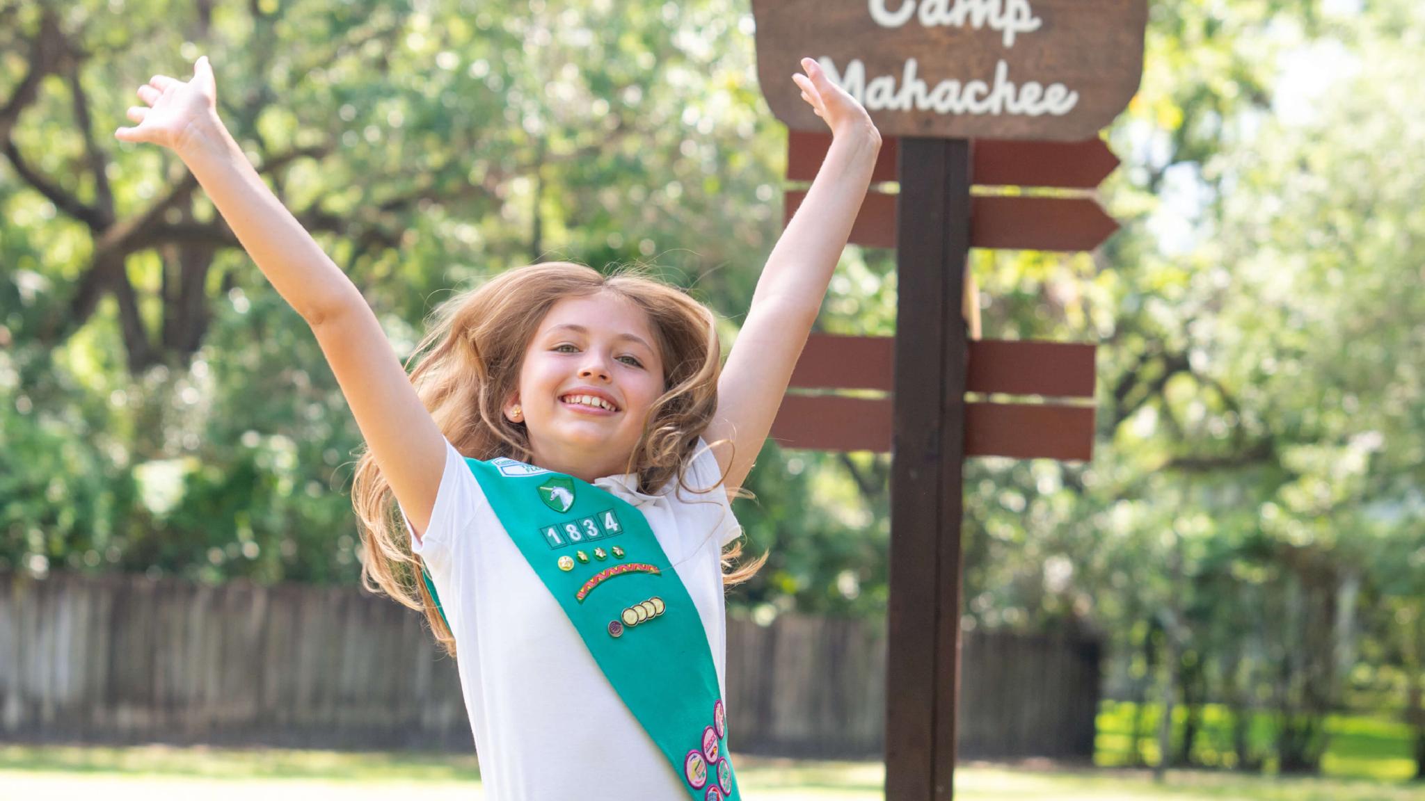 Girl Scout jumping at Camp Mahachee sign