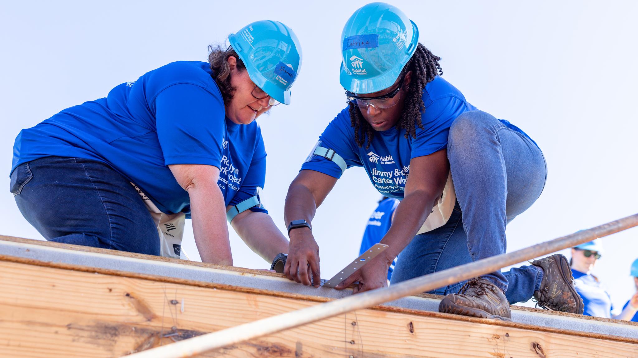 two women in hard hats building a house