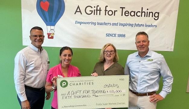 two publix employees present a $50,000 charity check to A Gift For Teaching