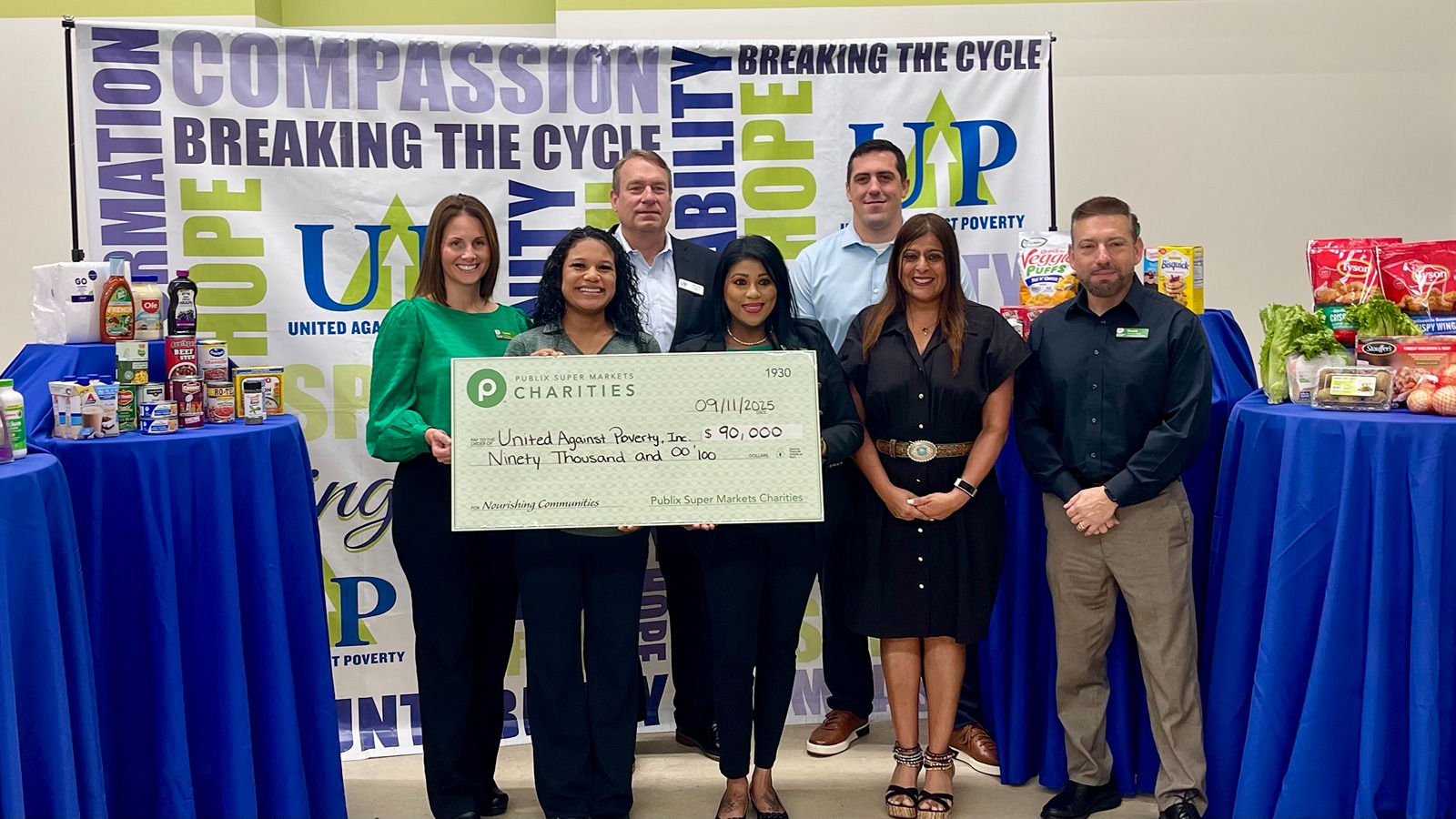 Team holding a giant charity check for United Against Poverty