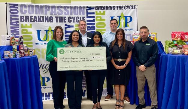 Team holding a giant charity check for United Against Poverty