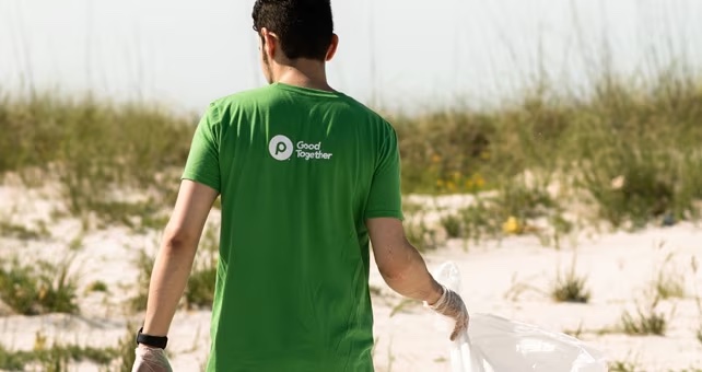 Publix associate picking up trash with publix serves shirt