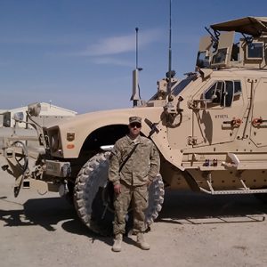 David in military uniform in front of a tank