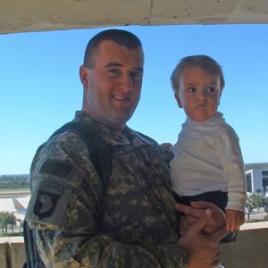 Thomas in military uniform holding his young son