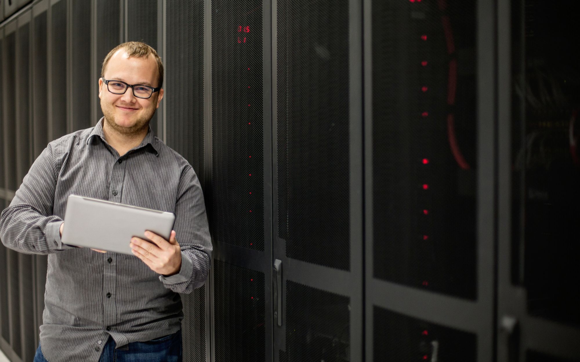 man holding a tablet by servers