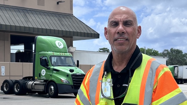 Oscar wearing a safety vest in front of a Publix truck