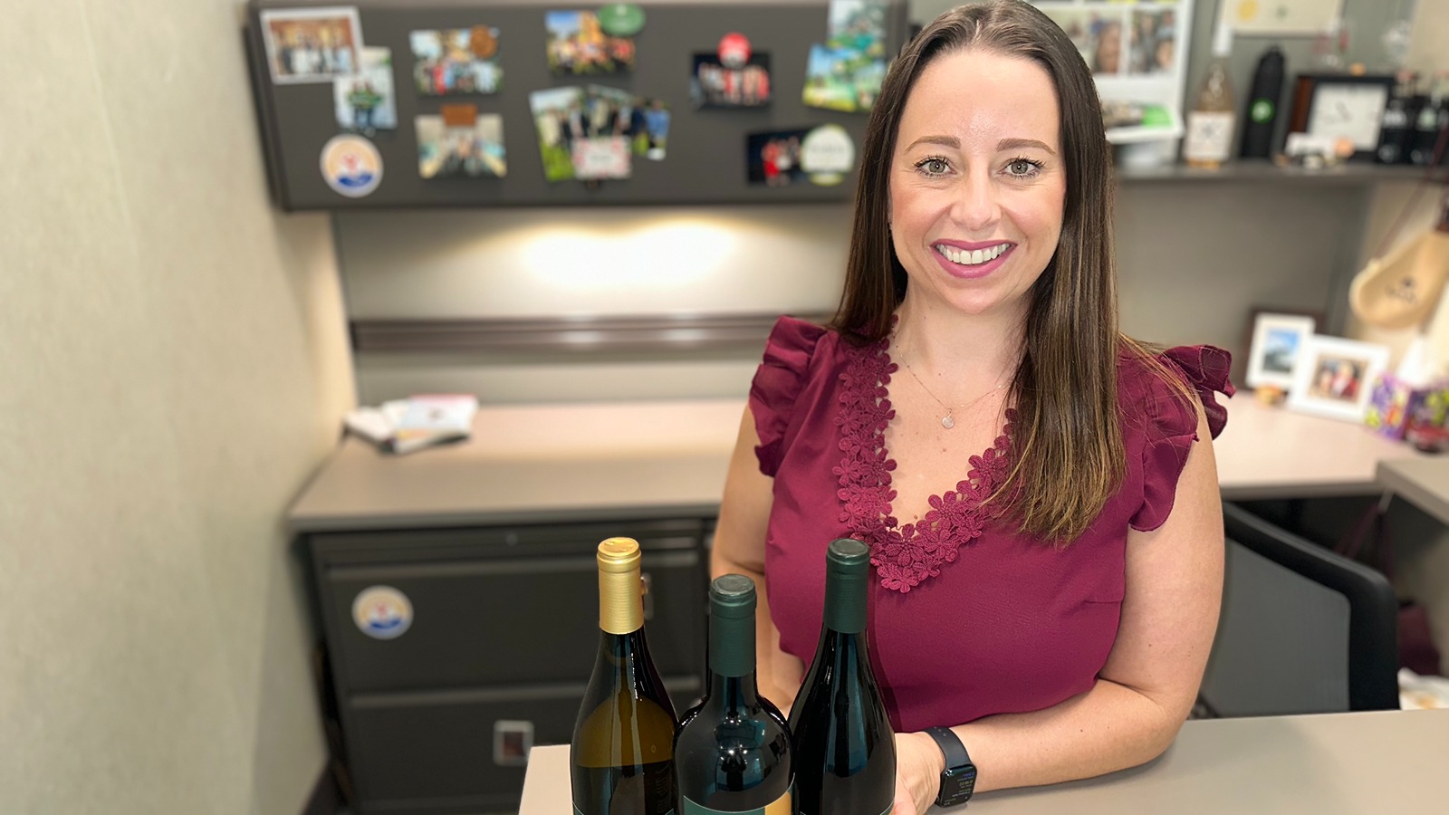wine buyer at her desk with bottles of wine