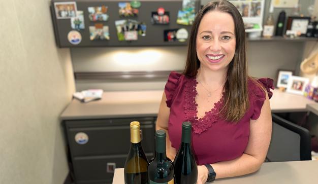 wine buyer at her desk with bottles of wine