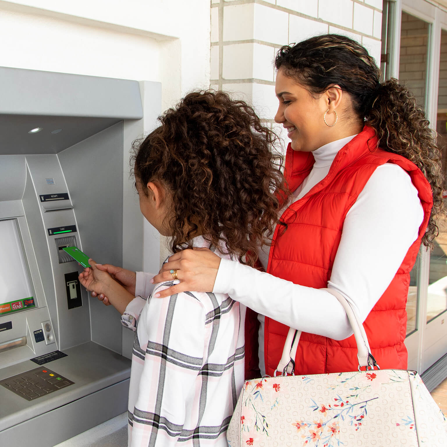 woman and girl using a debit card at an Presto ATM