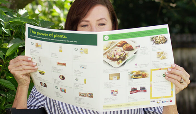a woman reading a publix weekly ad flyer