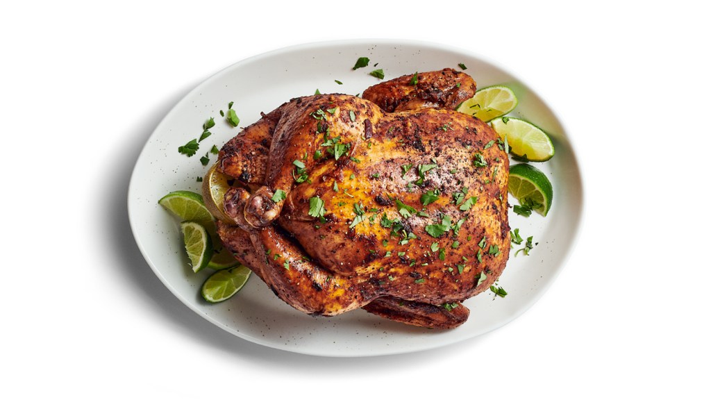 Plate of whole roasted chicken with lime and cilantro.
