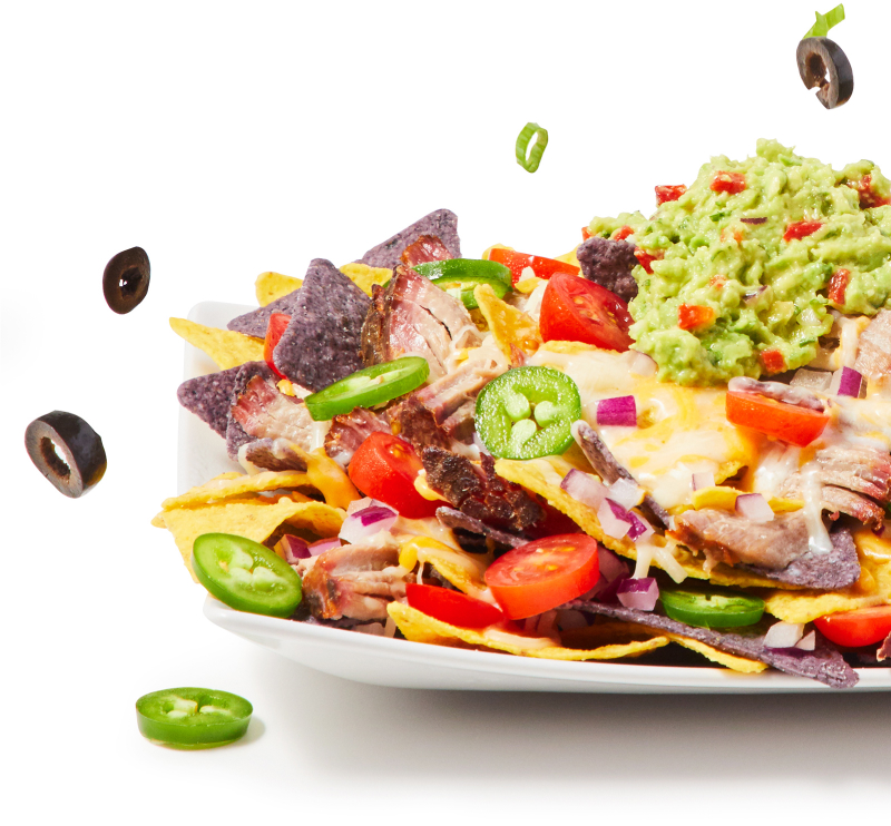 platter of nachos with pork, black olives, tomatoes, jalapenos, and guacamole