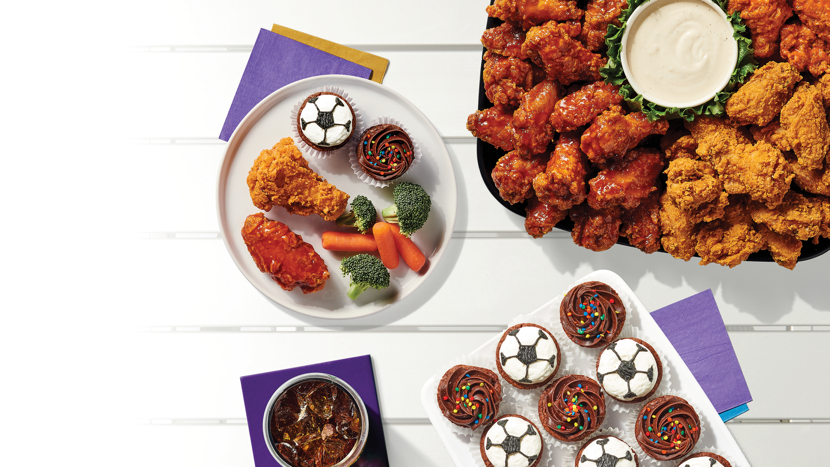 table of catered platers including cupcakes, veggies, and chicken wings at a tailgate for Orlando City soccer games